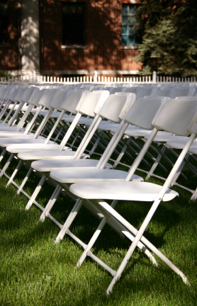 wedding white plastic with metal folding chairs set up in an outdoor setting on grass.